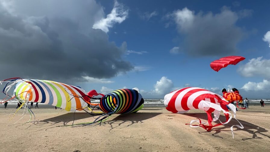 Große bunte Drachen liegen und fliegen am Strand von Lakolk beim Rømø Drachenfestival