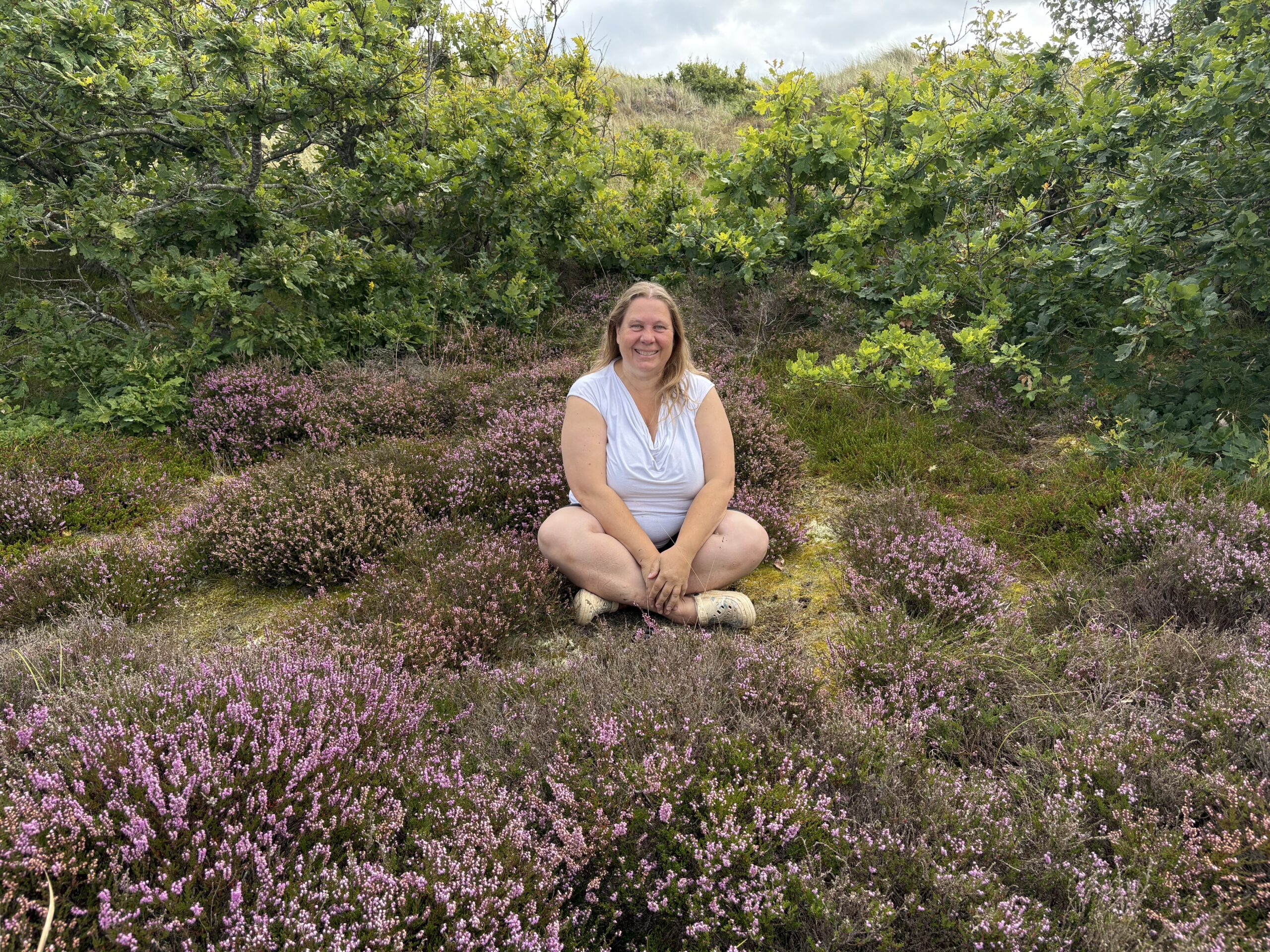 Heike Engel sitzt ruhig in der blühenden Heide