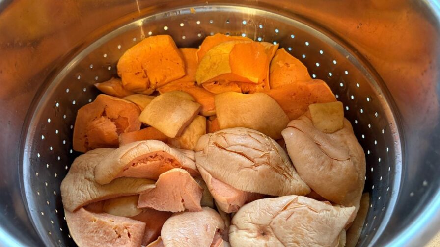 Weiche, blass gewordene Quittenstücke im Fruchtkorb des Dampfentsafters nach dem Entsaften
