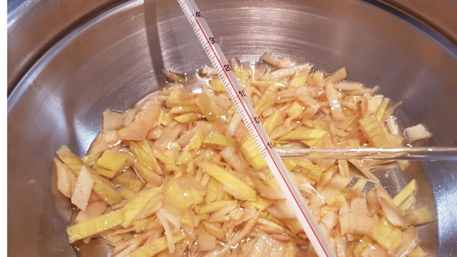 Quittenschalen in Öl im Wasserbad mit Thermometer beim Warmauszug